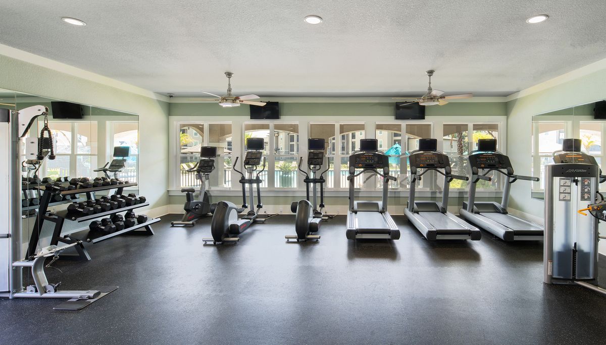 Fitness center with ceiling fans, recessed lighting, treadmills, ellipticals, free weights, weight machines, mirrored walls, and windows that face the pool courtyard