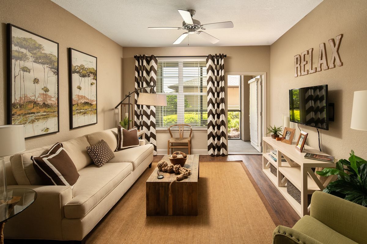 Furnished apartment living room with wood flooring, a ceiling fan with light, and door that opens to a screened-in patio